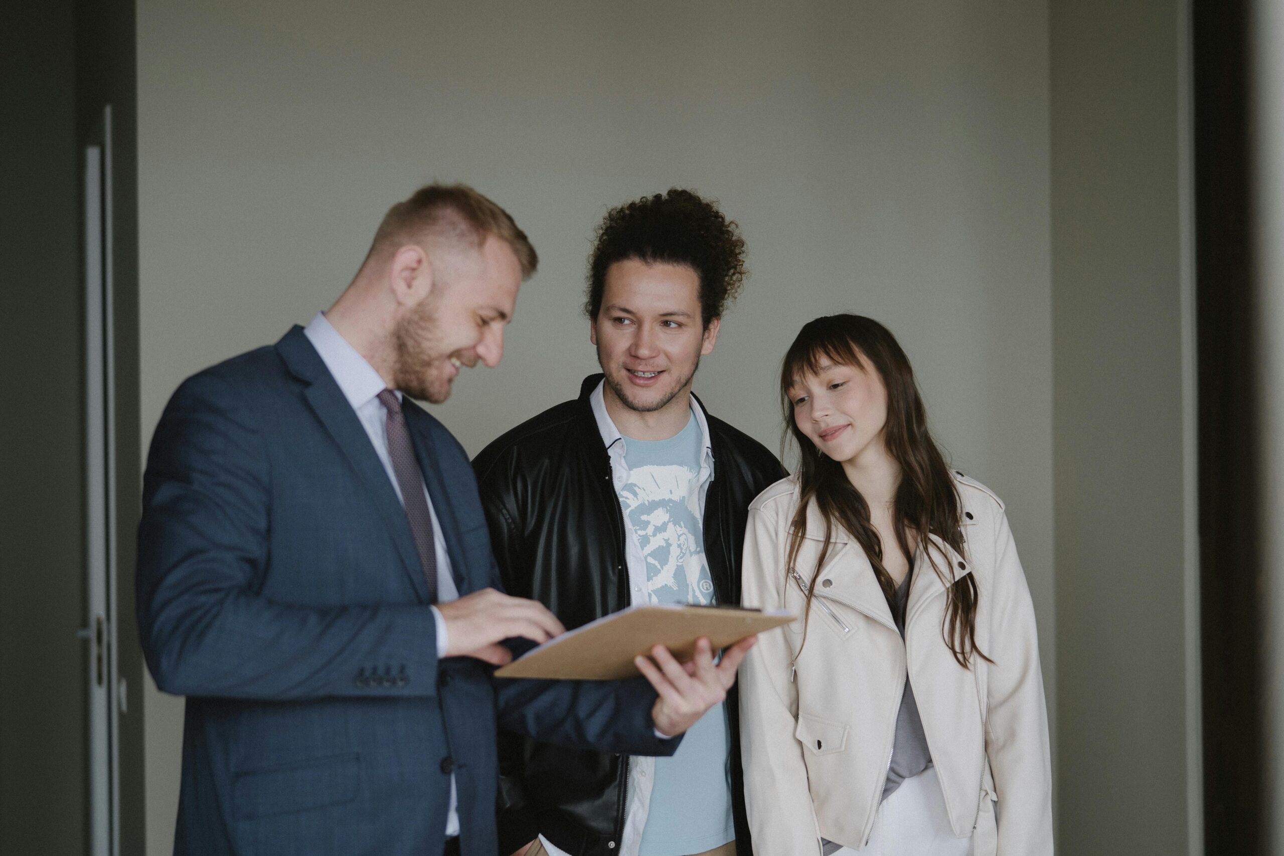 Three individuals in an apartment examining a clipboard, engaged in discussion and reviewing information together.